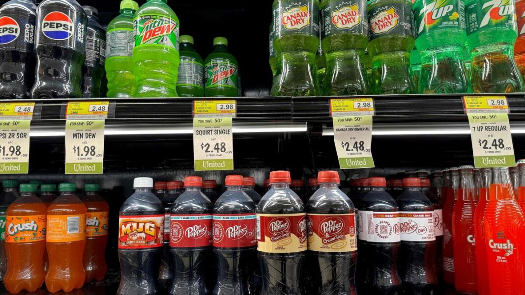 Variety of soda bottles on supermarket shelf.
