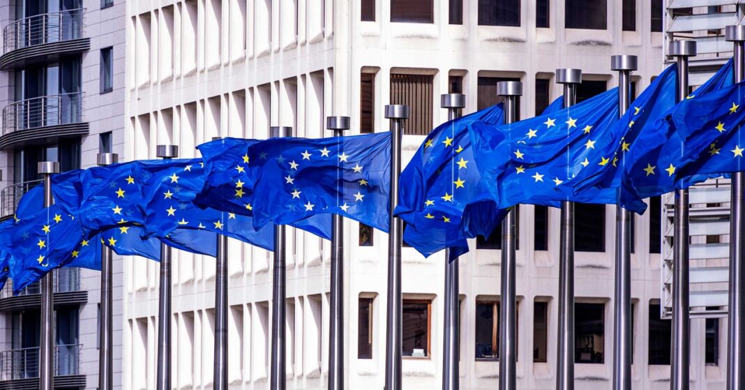 European Union flags fluttering outside modern building.