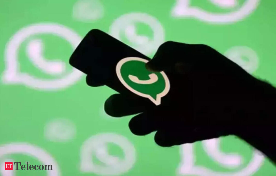 Hand holding smartphone with WhatsApp logo displayed.