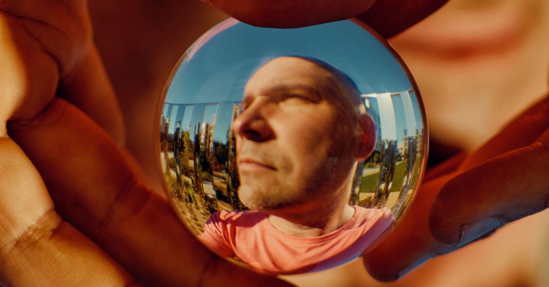 Man reflected in crystal ball held by hands.