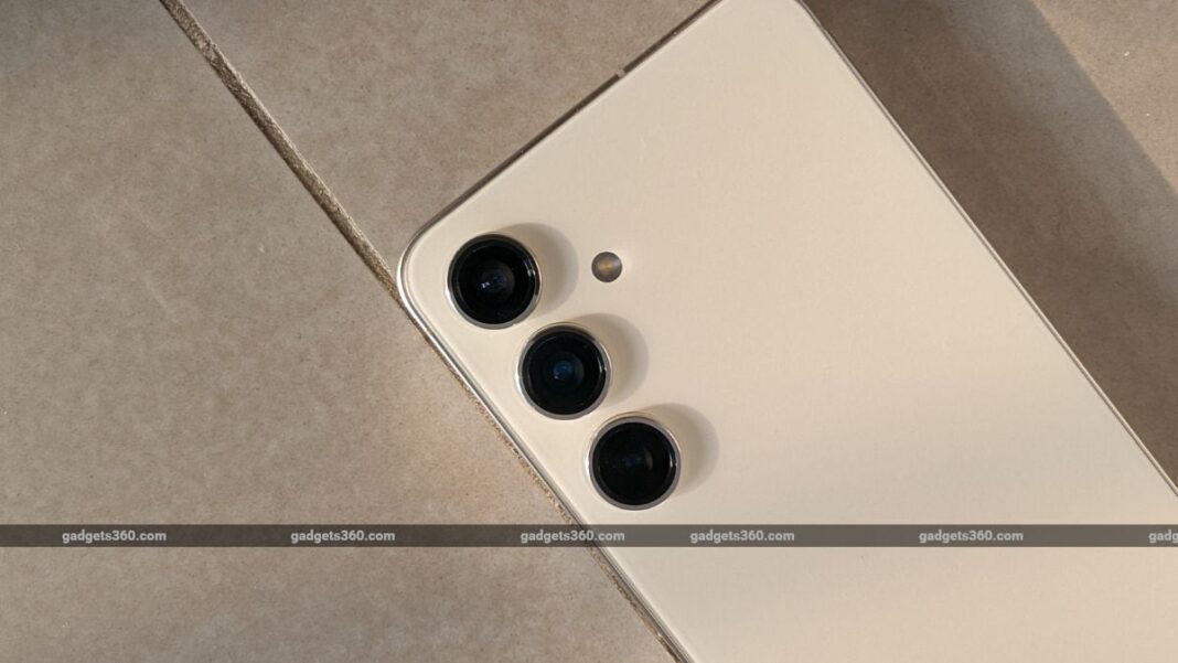 Smartphone with triple camera setup on tile surface.