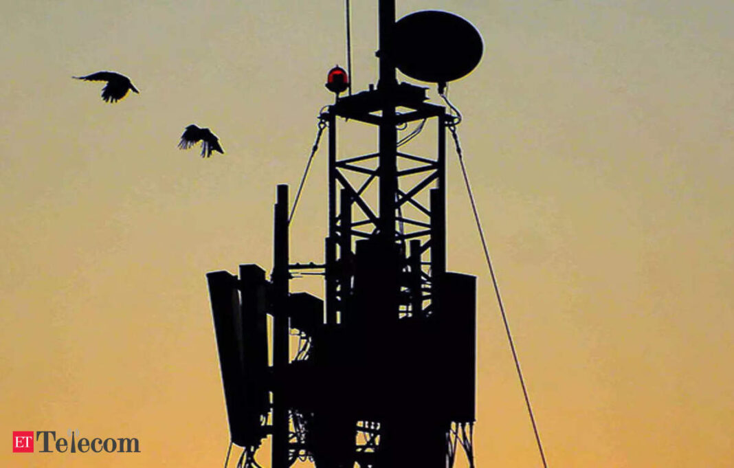 Silhouette of a cell tower at sunset with birds.