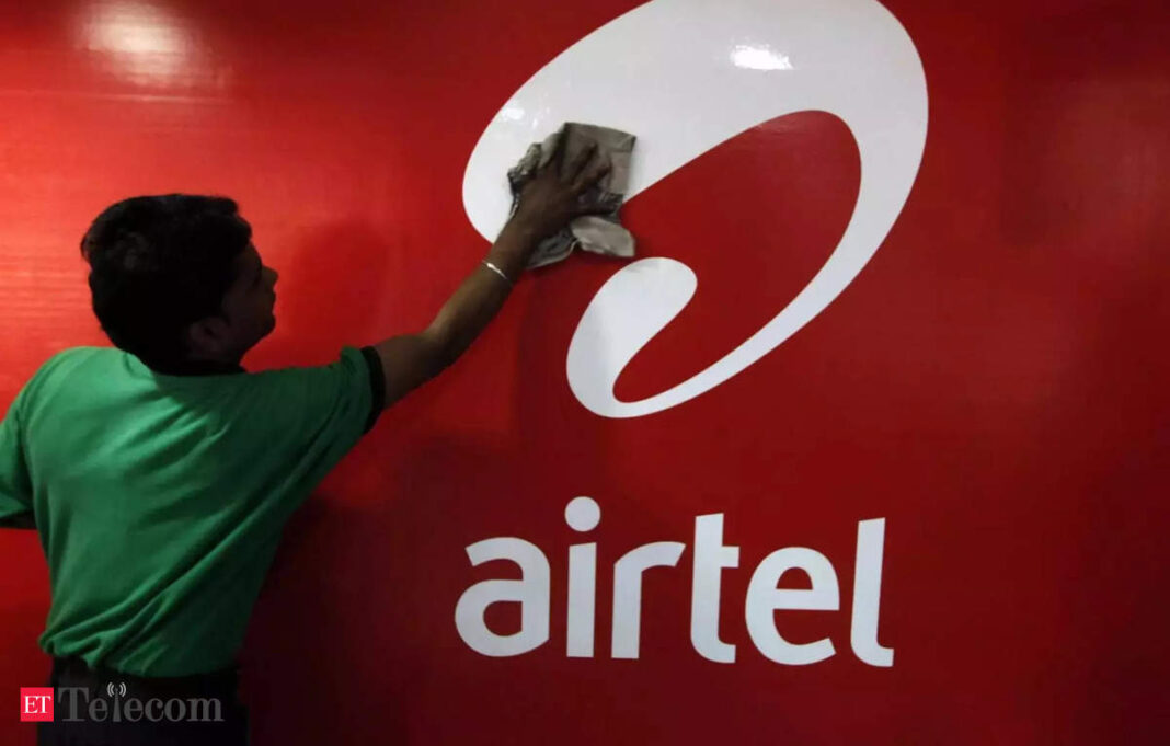 Worker cleaning Airtel logo on red background.