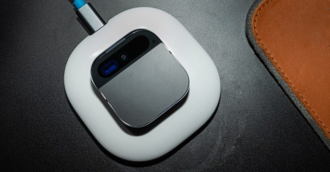Wireless mouse on black surface beside leather object.