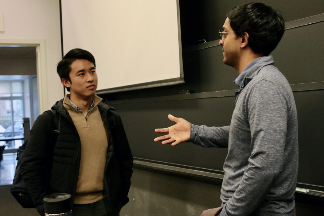 Two men talking in a classroom setting.