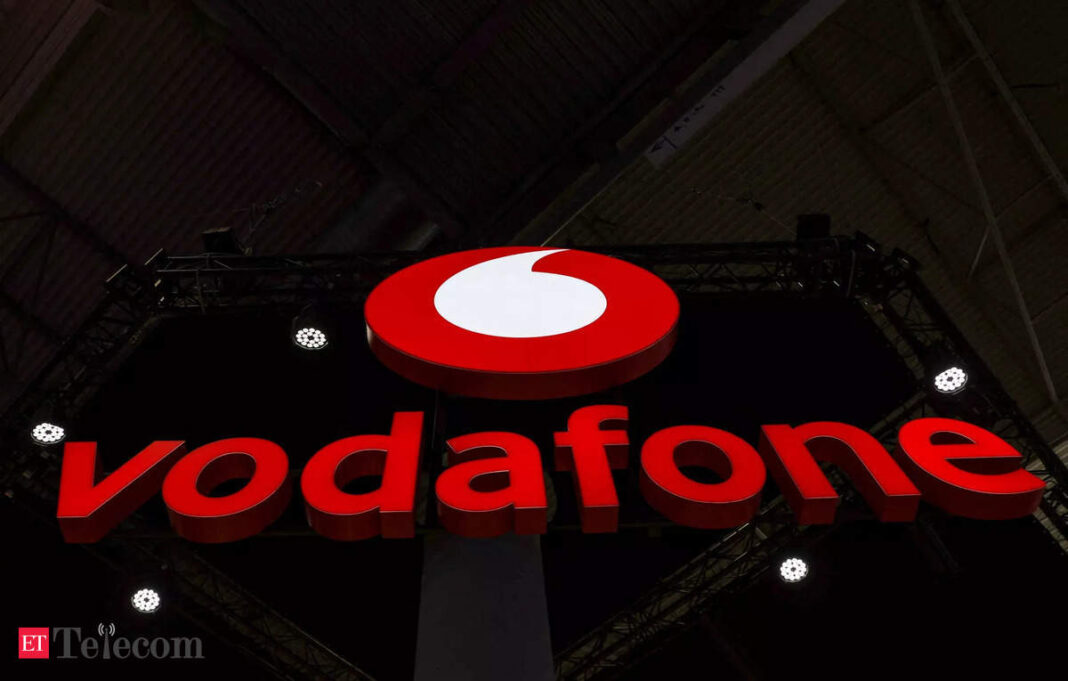 Vodafone brand sign illuminated at night.