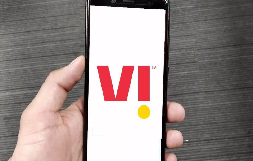 Hand holding smartphone displaying red and yellow logo.