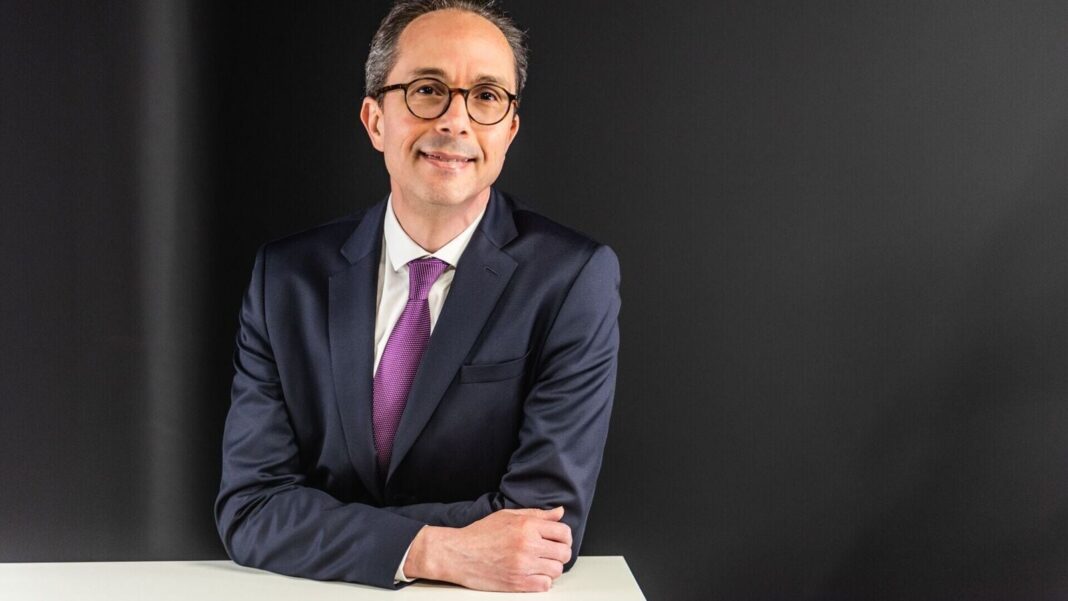 Smiling businessman in suit leaning on table.