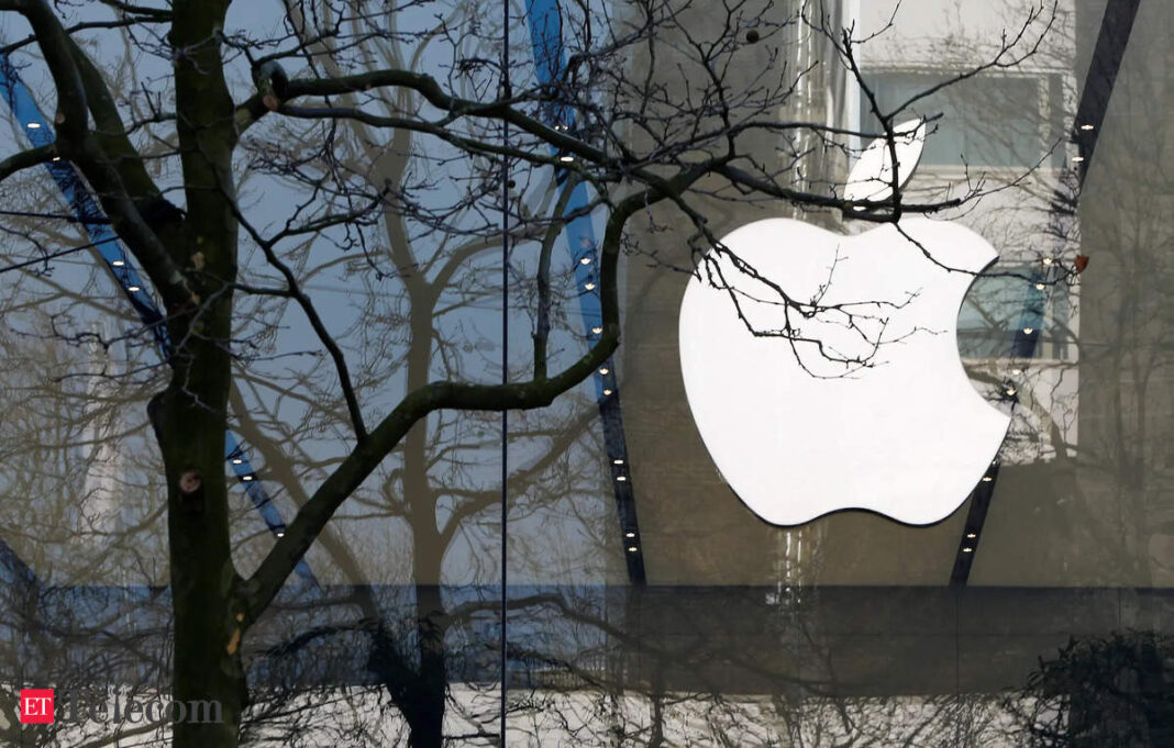 Apple logo on building behind leafless tree branches.