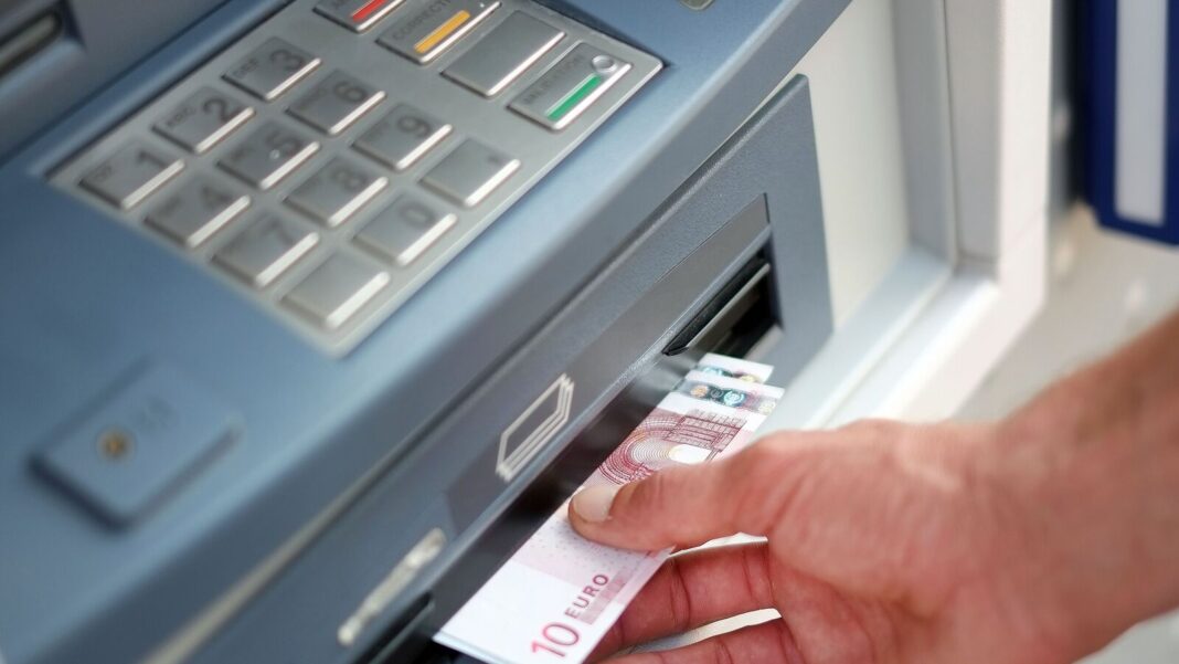 Person withdrawing cash from ATM machine.