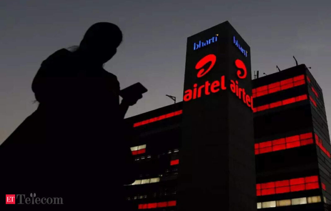 Silhouette of person against illuminated Airtel building at dusk.