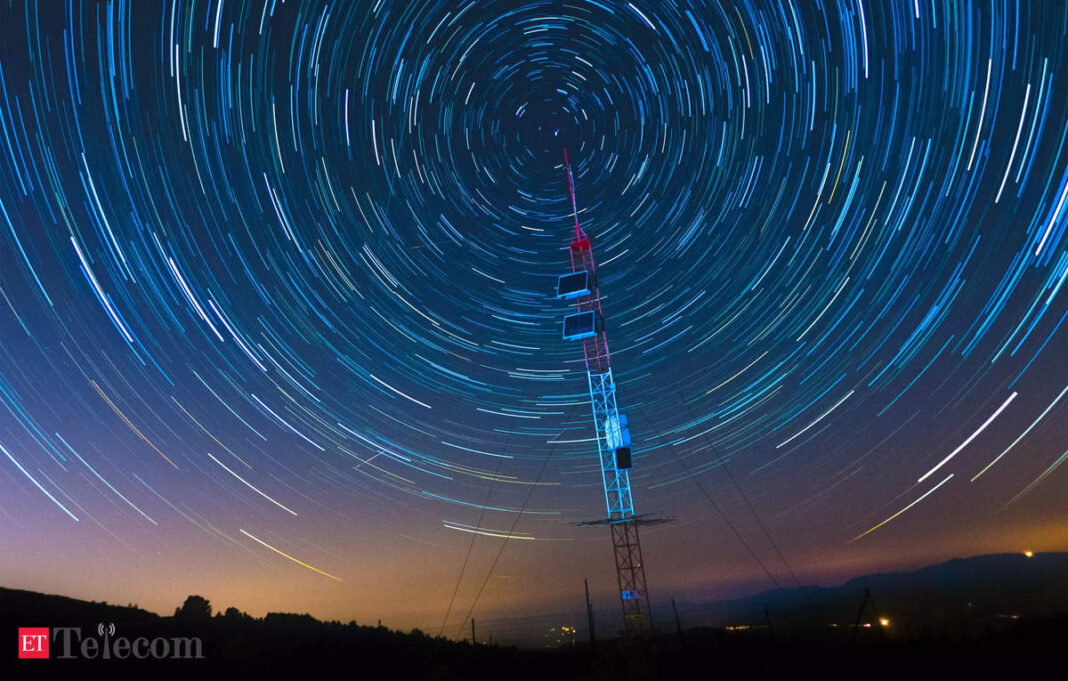 Star trails circling above communication tower at night.