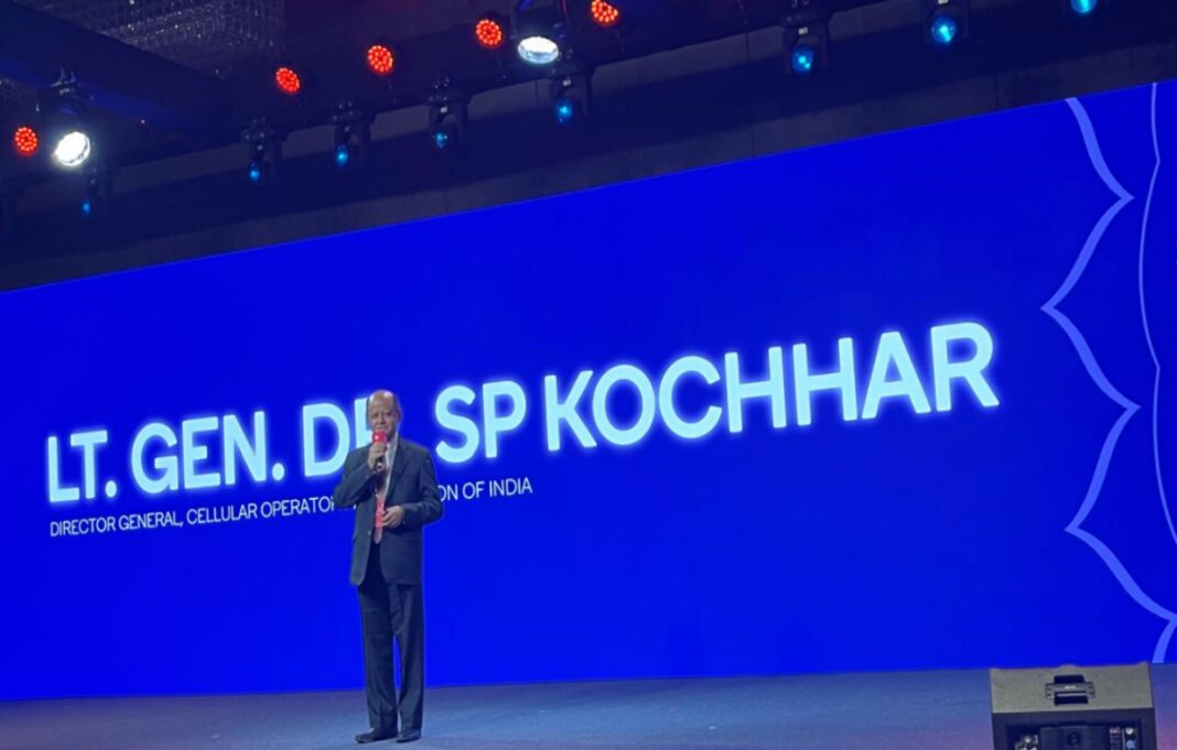 Man speaking at conference with name backdrop.