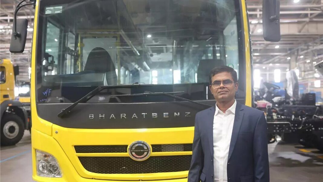 Man standing in front of BharatBenz bus at factory.