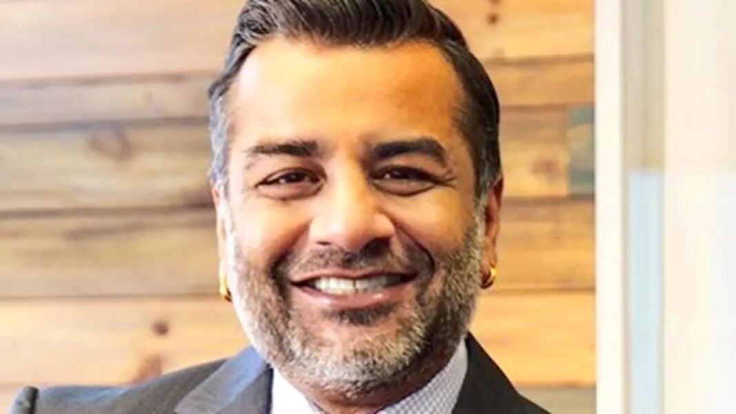 Smiling businessman in suit with wooden background.