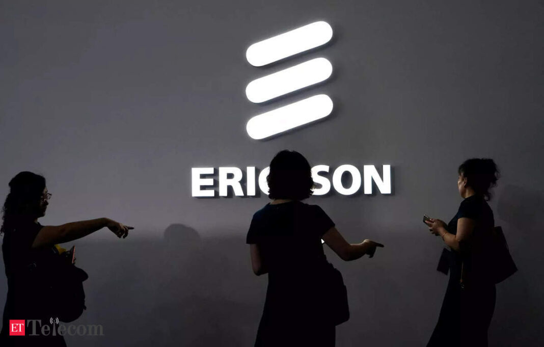 People silhouetted against illuminated Ericsson logo.