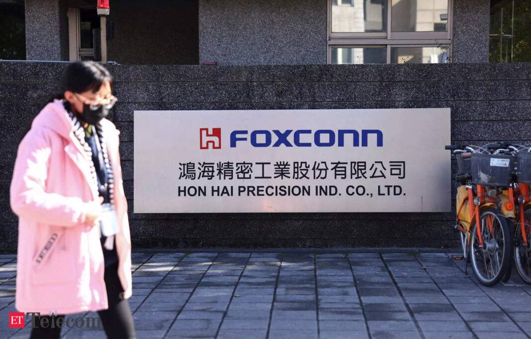 Person walking by Foxconn signboard with bicycles.