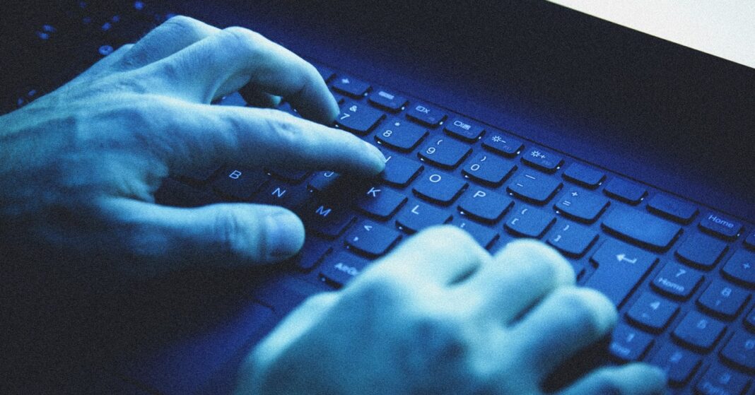 Person typing on blue backlit keyboard.