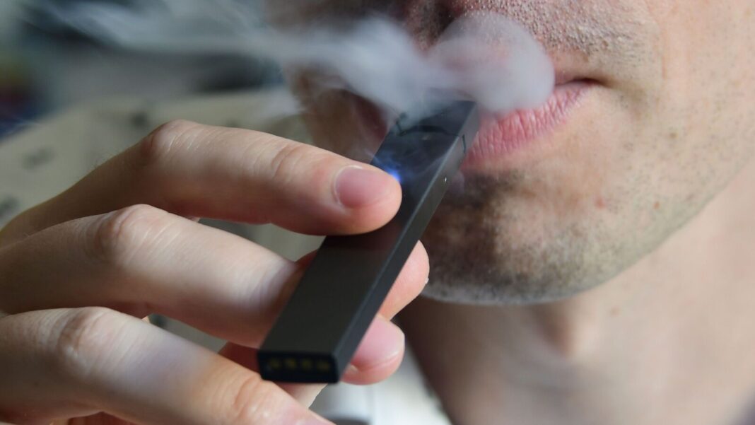 Person using an electronic cigarette exhaling vapor