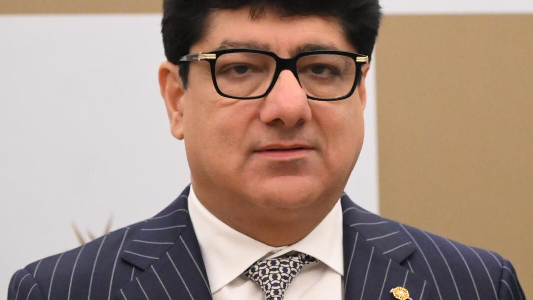 Man in glasses and striped suit looking serious.