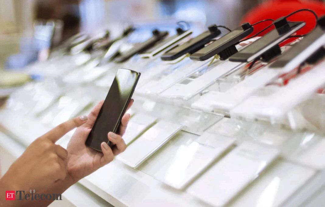 Hand examining smartphones at electronics store display.