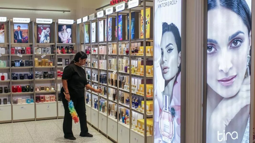 Woman browsing perfumes in cosmetics store aisle.