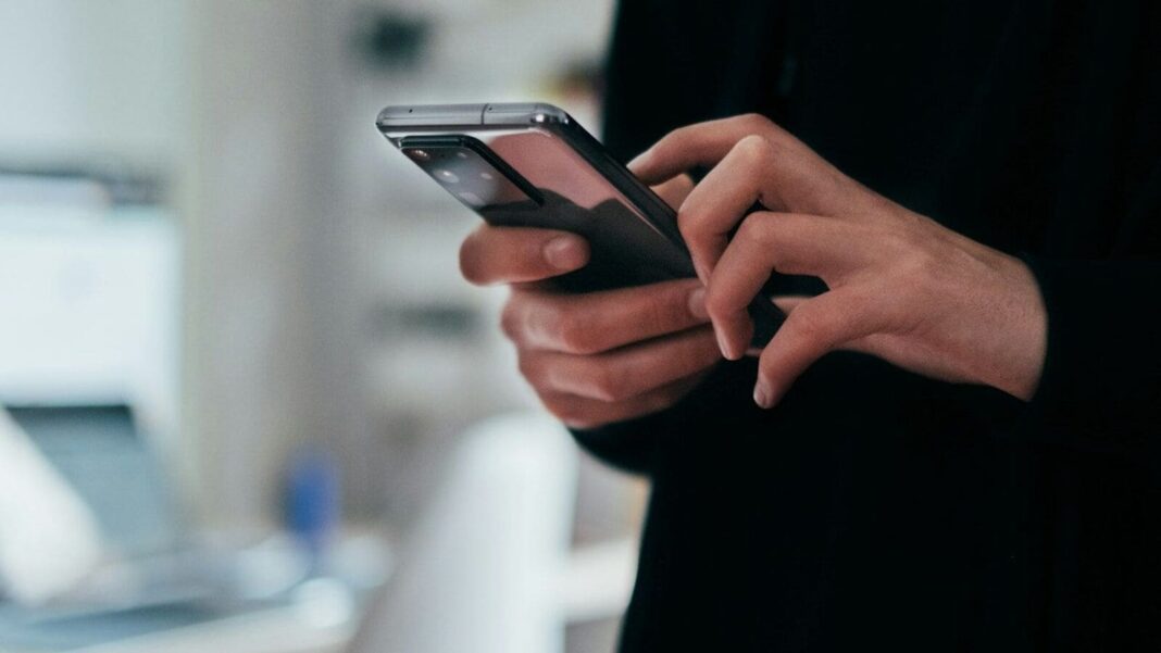 Person using smartphone in a modern setting.