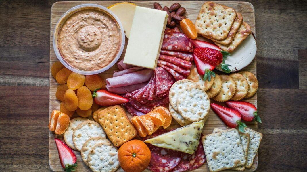 Gourmet cheese and charcuterie board with fruits and nuts.