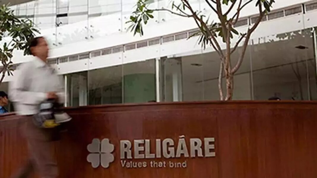 Person walking past Religare office building with signage.