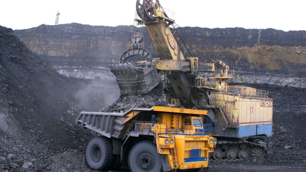 Excavator loading coal onto large mining truck.