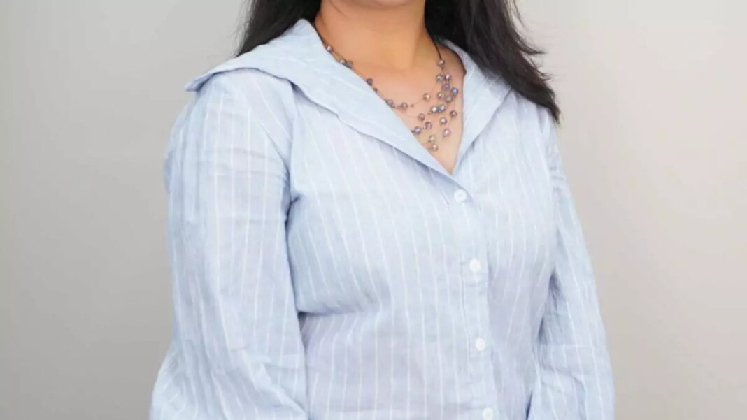 Woman in blue striped shirt with necklace.