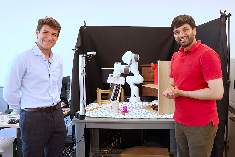 Two engineers presenting robotic arm in laboratory.