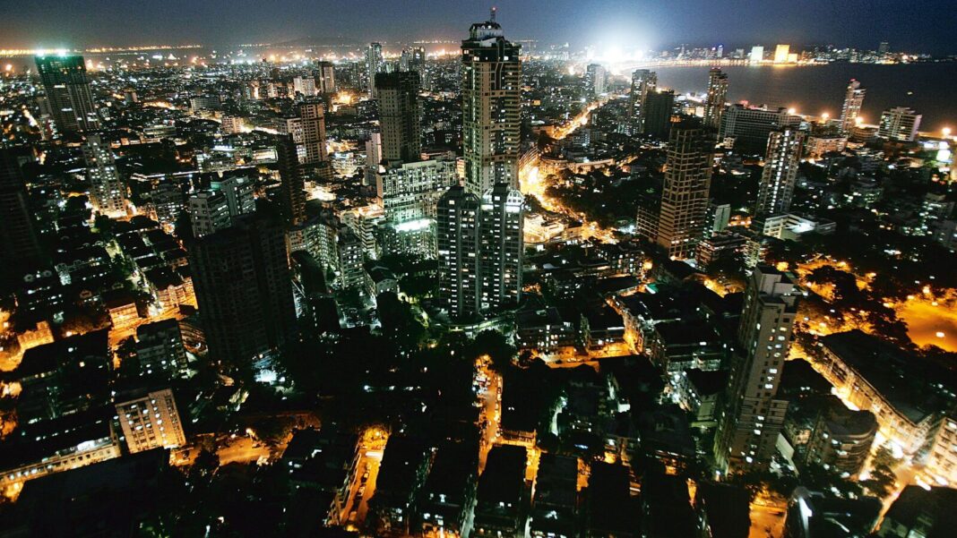 Nighttime aerial view of illuminated cityscape near coast.