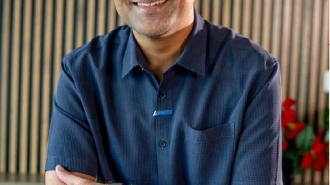 Smiling man in a blue shirt, arms crossed.