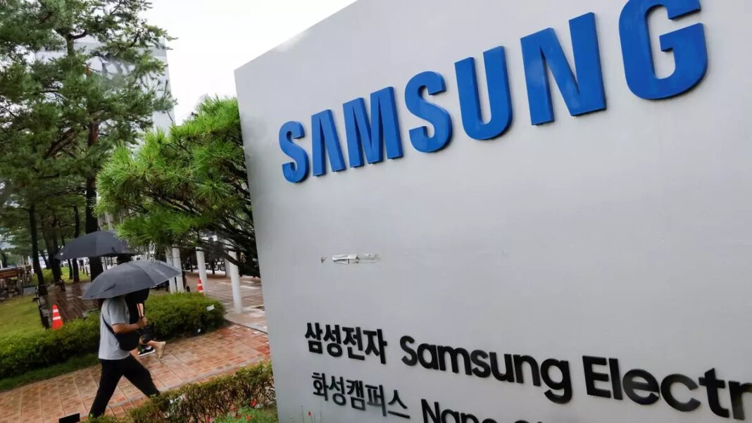 Person with umbrella near Samsung sign in rain.