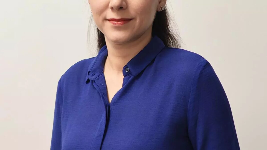 Woman smiling in blue shirt, professional headshot.