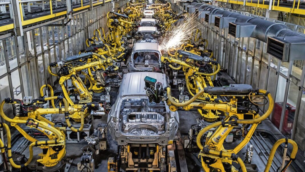Robotic arms assembling cars in factory.