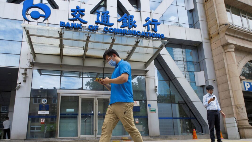 Pedestrians using smartphones outside Bank of Communications.