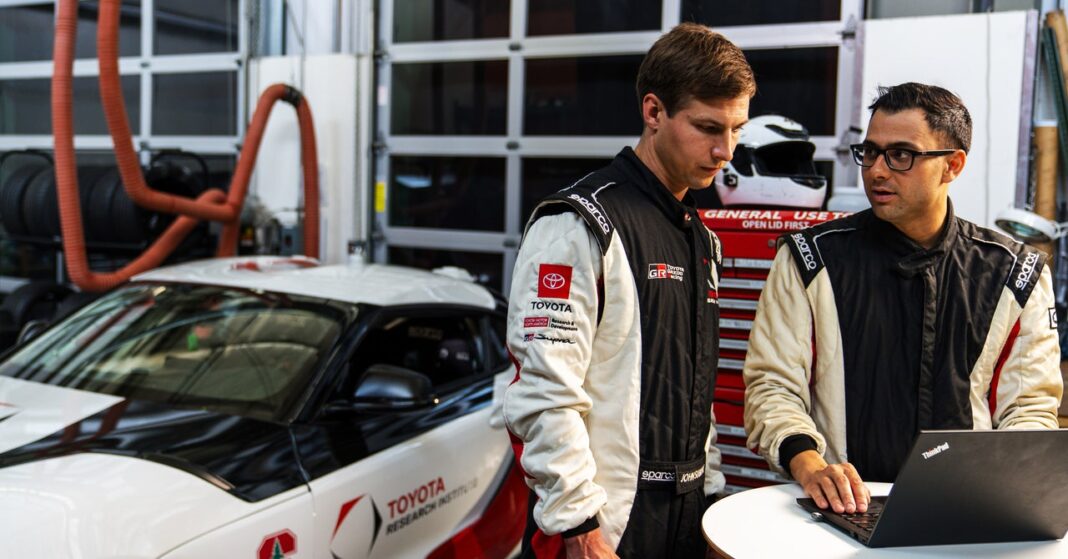 Racing team members discussing over laptop near car