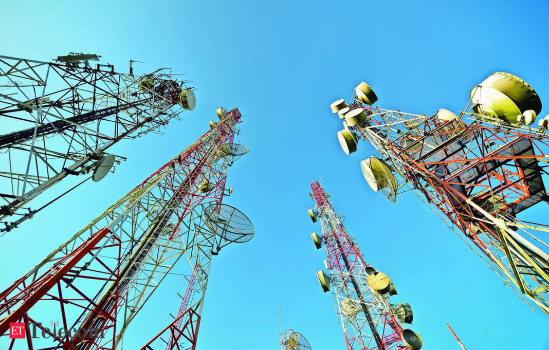 Multiple telecommunications towers against blue sky.