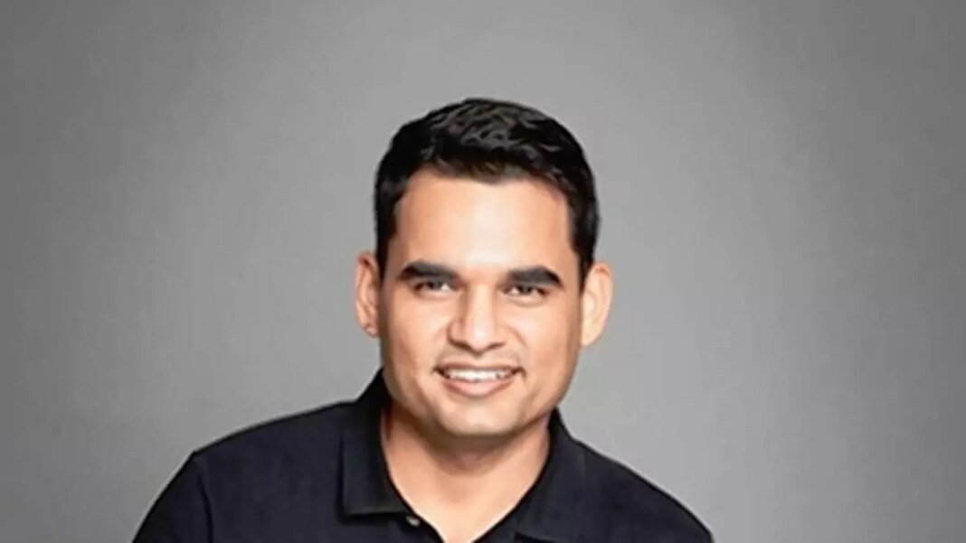 Man smiling, black shirt, gray background.