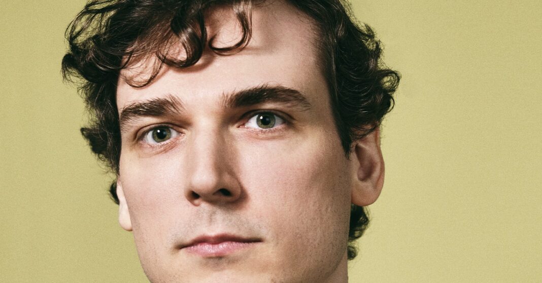 Man with curly hair against green background.