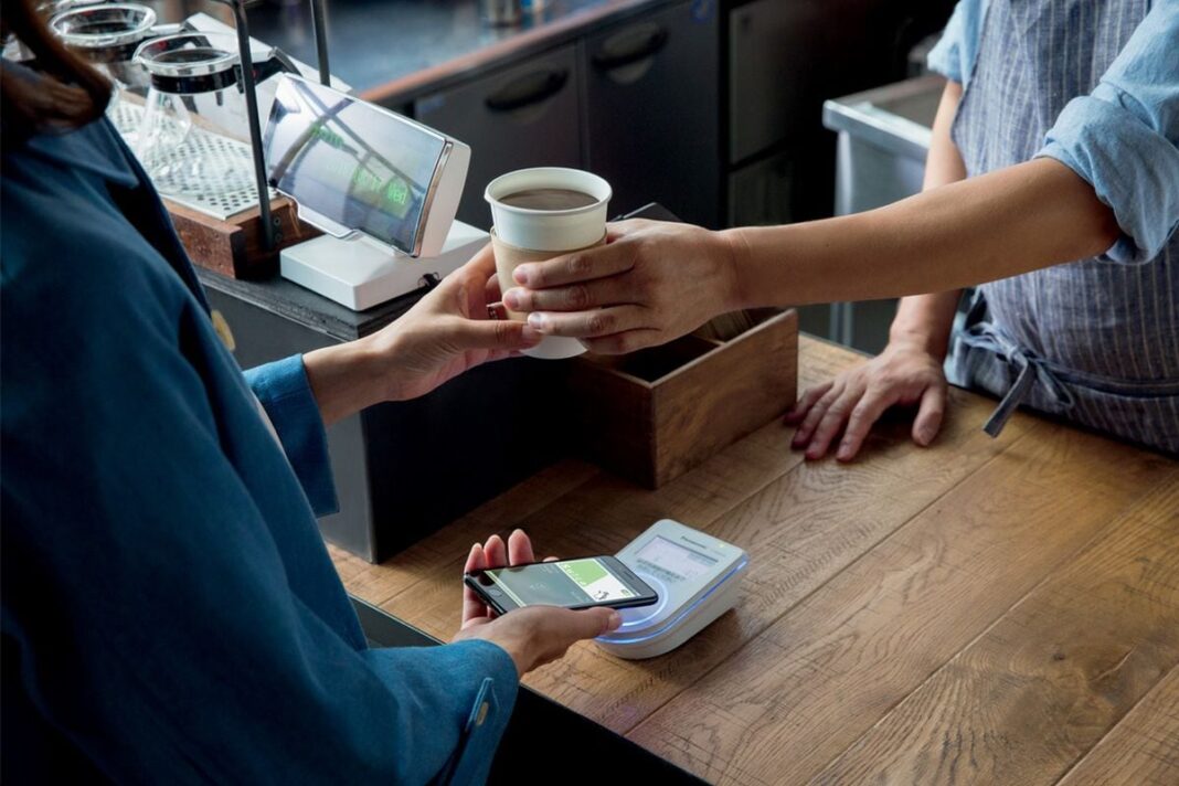 Person receiving coffee while mobile payment is processed.