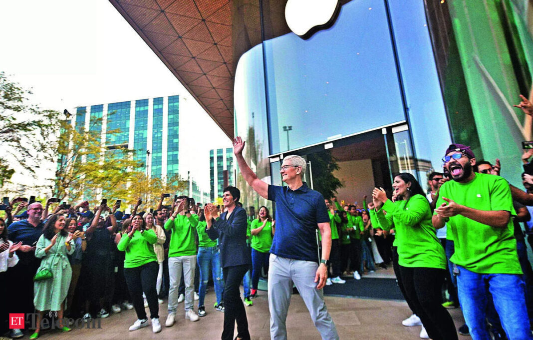 Man waving to cheering crowd near glass-fronted building.