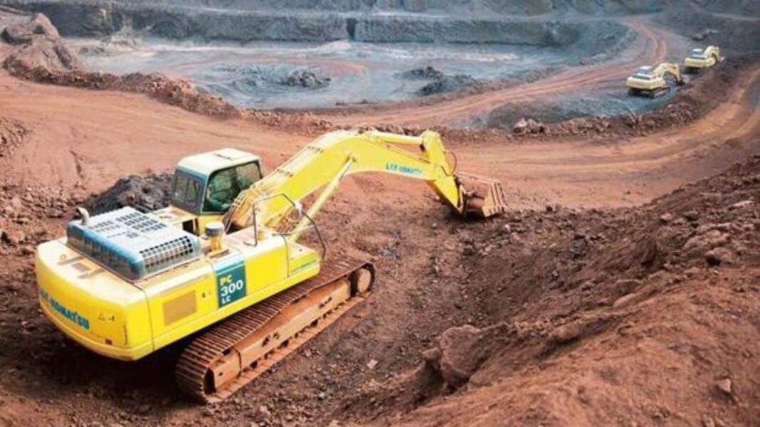 Yellow excavator at construction site with trucks.