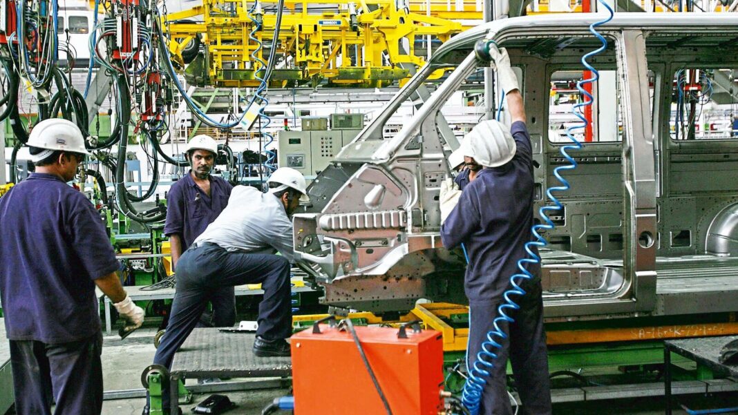 Workers assembling vehicle at automotive manufacturing plant.