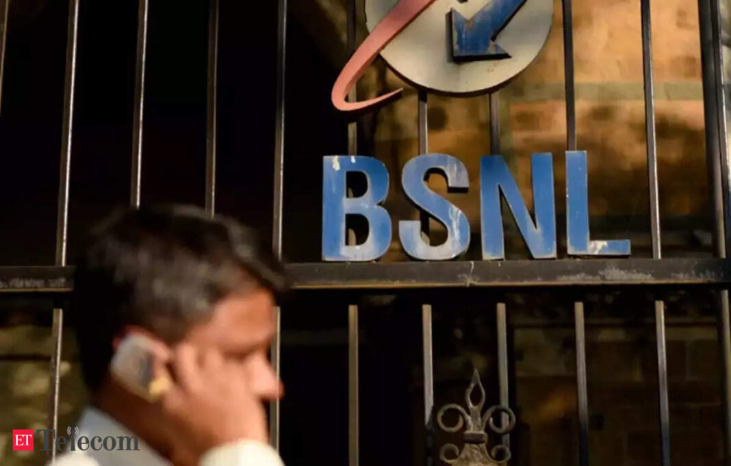 Man on phone near BSNL sign on storefront grille.