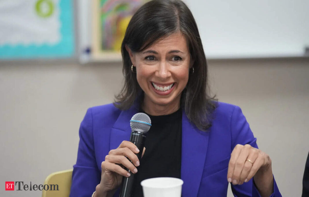 Woman in blue blazer speaking into microphone.