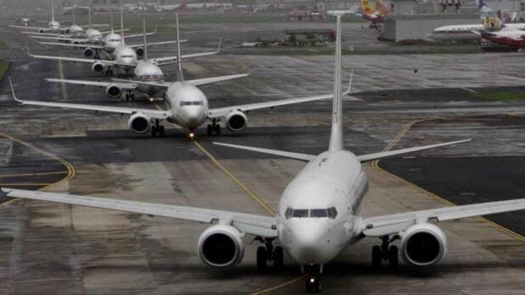 Queue of airplanes on wet taxiway.