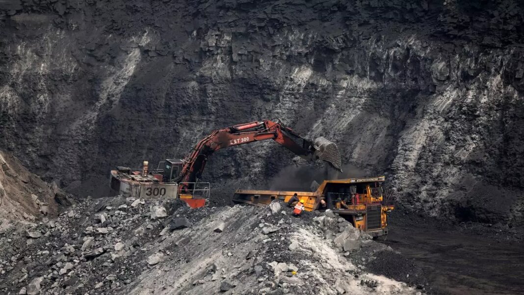 Excavator loading coal into mining truck at site.